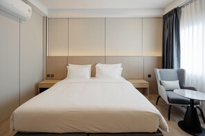 A hotel room with a large bed, bedside tables, a chair, and a small table. - HippoTel Khaorang Phuket Town (Phuket)