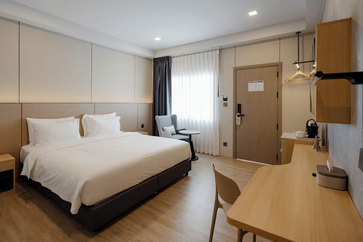 Une chambre d’hôtel comprenant un lit, une table de chevet, une chaise, un bureau et une armoire.