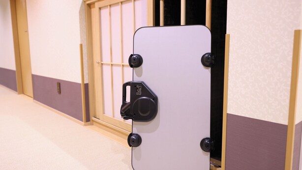 A door with a security lock, a wooden frame, and a wall with a patterned design.