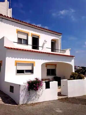 A two-story building with a white facade, red-tiled roof, and a small balcony. - Oceanfront house in Benagil (Lagoa)