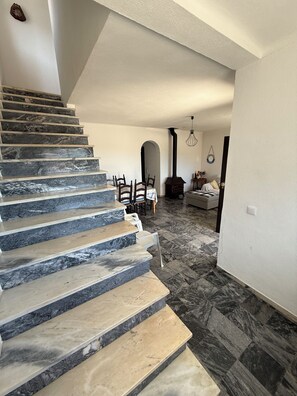 A staircase with alternating marble and wood steps leading to a dining area with a table and chairs. - Oceanfront house in Benagil (Lagoa)
