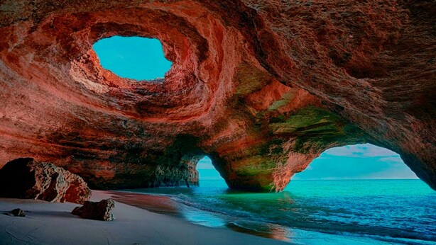 A natural rock formation with a circular opening and a beach in the foreground. - Oceanfront house in Benagil (Lagoa)