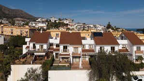 A residential area with houses featuring red-tiled roofs, balconies, and solar panels. - Spacious 4BR Townhouse - Rooftop Terrace (Fuengirola)