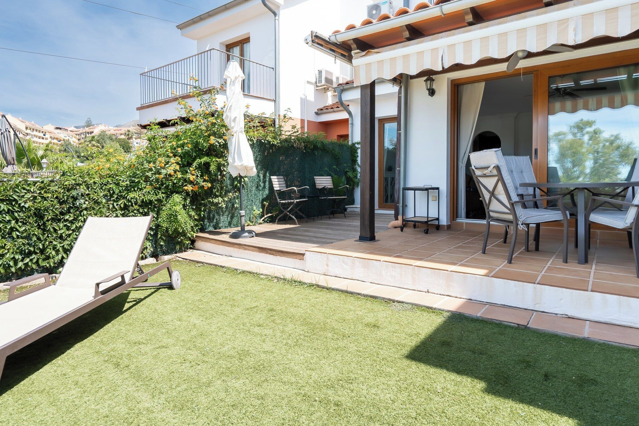 Une terrasse avec des meubles d’extérieur, un espace salon abrité et une vue sur les bâtiments environnants.