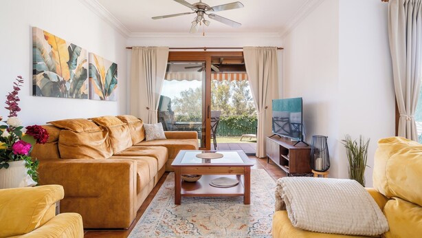 A living room with a sofa, a coffee table, a TV, and a ceiling fan. - Spacious 4BR Townhouse - Rooftop Terrace (Fuengirola)