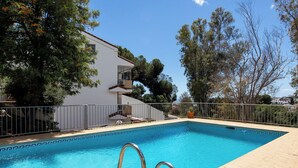 A swimming pool with a metal ladder, surrounded by a fence, and a building with a balcony. - Spacious 4BR Townhouse - Rooftop Terrace (Fuengirola)
