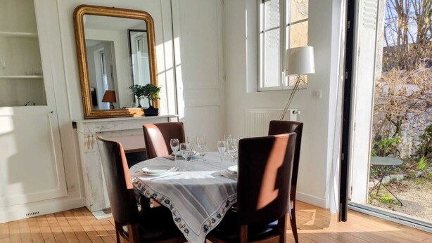 Un comedor con una mesa preparada para cuatro, un espejo y vista al exterior.