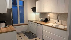 Una cocina moderna con armarios blancos, una cafetera negra, un fregadero y una ventana con persianas.