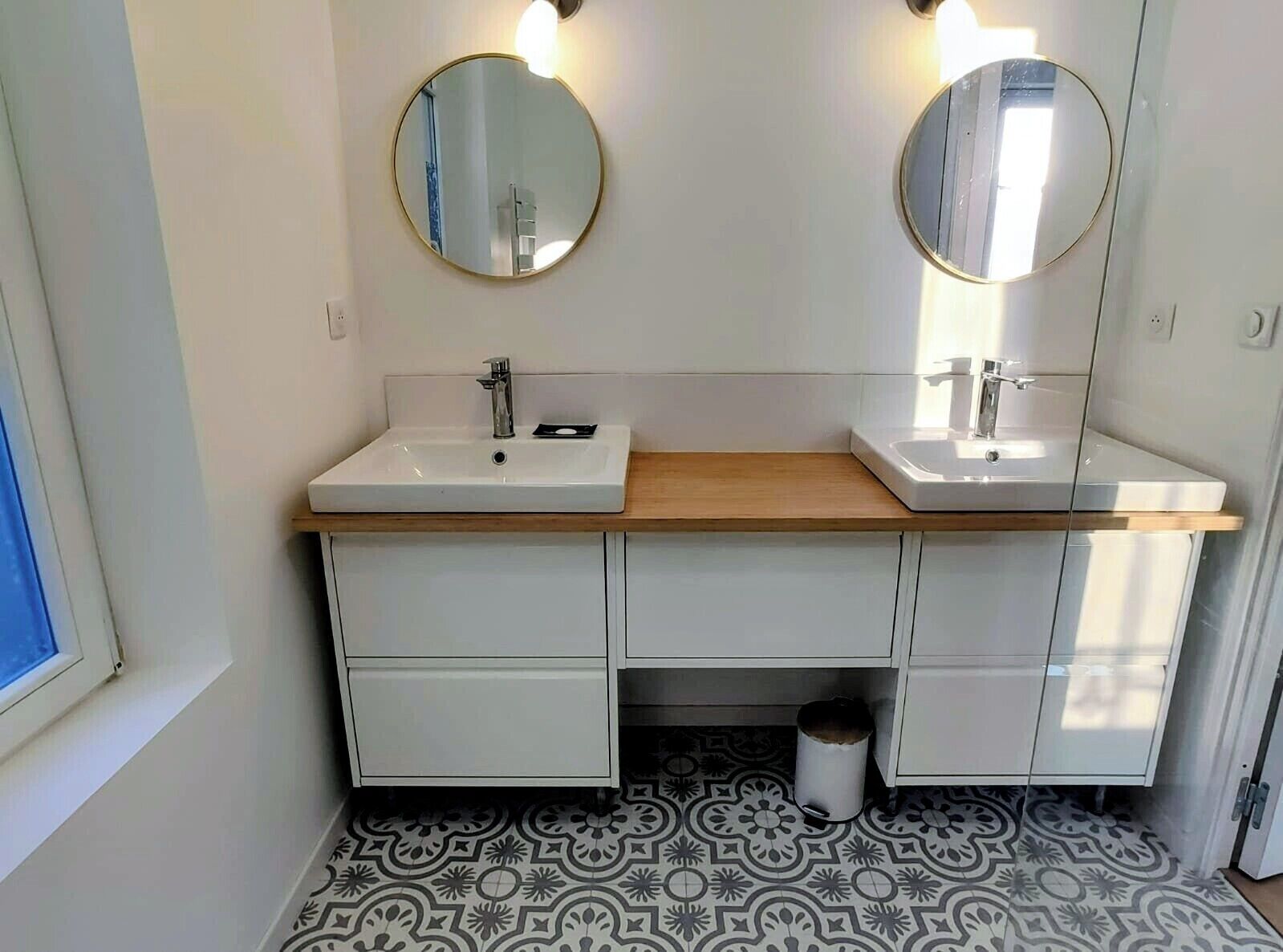 Une salle de bain avec deux lavabos, un miroir au-dessus de chacun, et des carreaux de sol à motifs.
