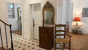 Una escalera con piso estampado, una silla de madera, un aparador y un espejo en la pared.