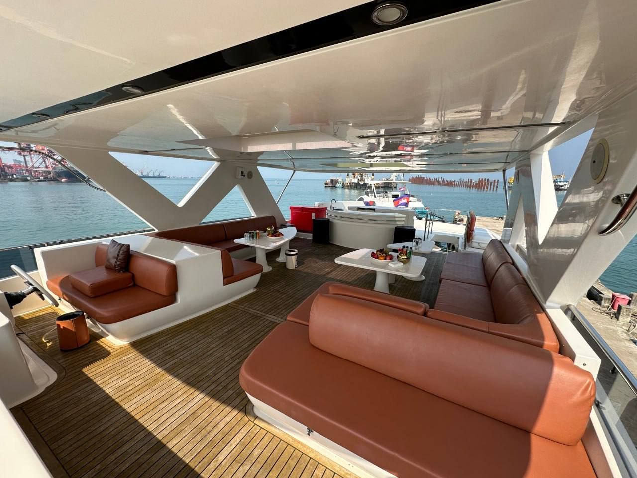 Ein Yachtdeck mit Sitzgelegenheiten, Tischen und Blick auf das Wasser.