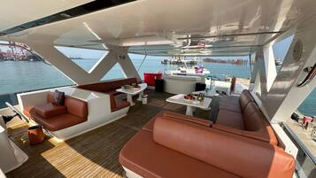 Ein Yachtdeck mit Sitzgelegenheiten, Tischen und Blick auf das Wasser.