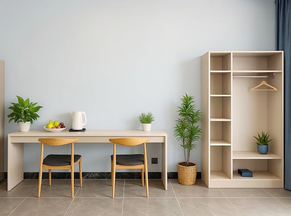 Une chambre moderne équipée d’un bureau, de deux chaises, d’une plante en pot, d’une machine à café et d’une armoire.