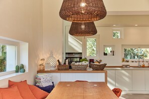 A modern kitchen with a wooden table, wicker baskets, and a hanging light fixture. - Terrarossa - charm and pool near the sea 2/4/6/8 pax (Puglia)