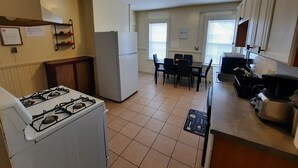 Une cuisine équipée d’une cuisinière, d’un réfrigérateur et d’un coin repas avec des chaises et une table.
