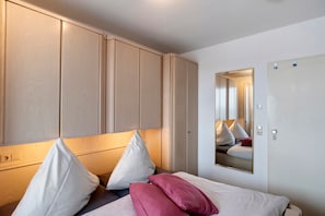 Une chambre d’hôtel avec un lit, des oreillers, un miroir et une armoire.