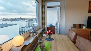 Un comedor con vistas a la ciudad, una mesa con sillas, un florero con flores y una lámpara.