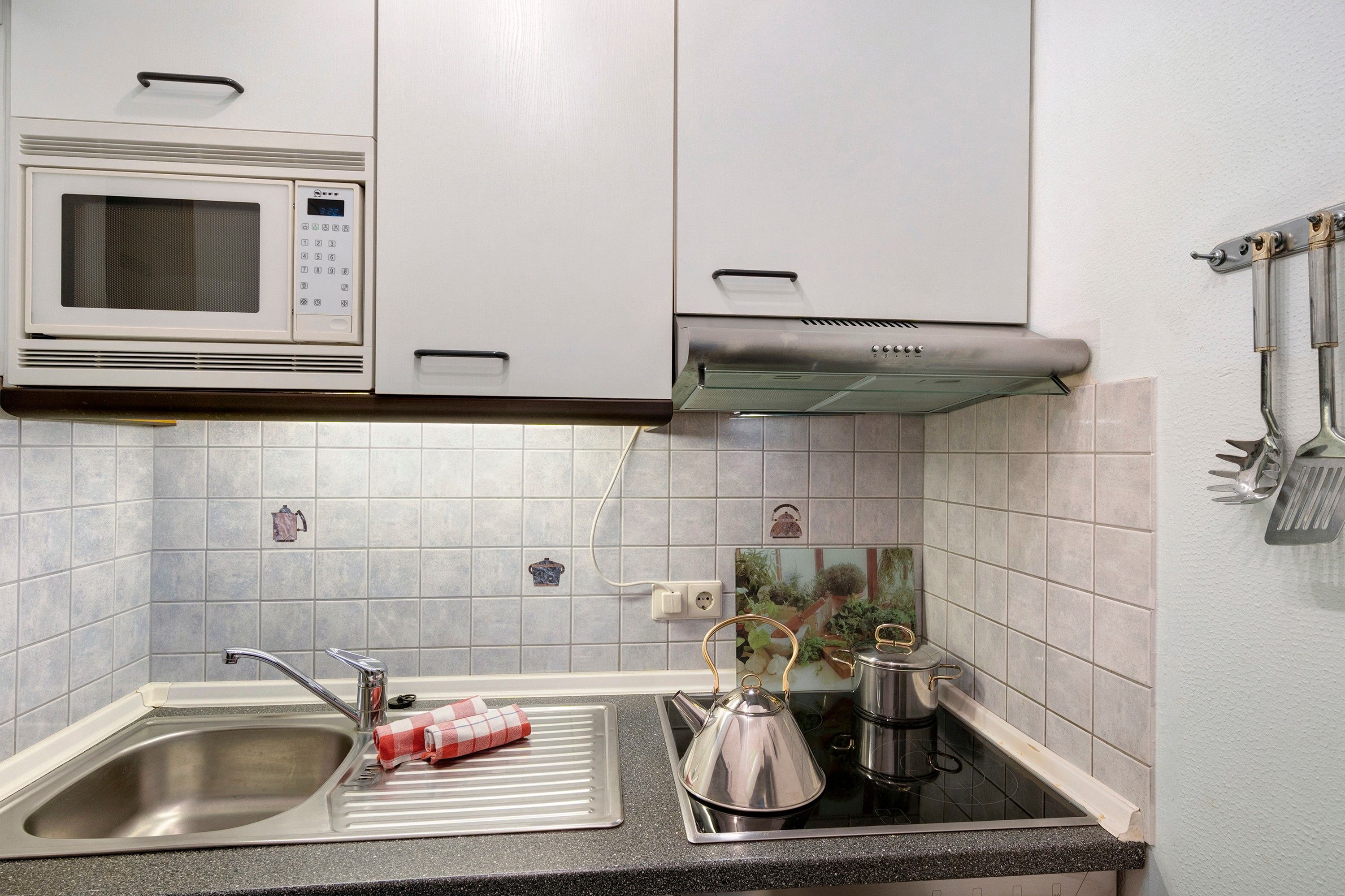 Une cuisine équipée d’un four à micro-ondes, d’une cuisinière, d’un évier et d’une bouilloire.