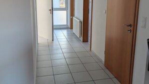 A hallway with white tiled flooring, wooden doors, and a radiator. - Vacation assembly apartment 2 bedrooms 3 beds A30 (Ibbenbüren)