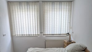 Ein Schlafzimmer mit Bett, Nachttisch, Lampe und Heizkörper.