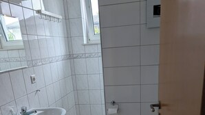 Ein Badezimmer mit Waschbecken, Toilette und einem kleinen Fenster.