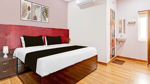 A bedroom with a bed, bedside table, lamp, air conditioning unit, and artwork on the wall. - Hotel O Ramarvapadu Near ESI Hospital (Penumuluru)