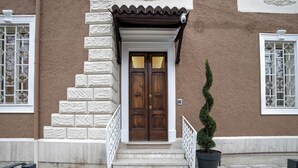 A building with a wooden door, white steps, a potted plant, and a 'WELCOME' mat. - GH Villa Poerio (Rome)