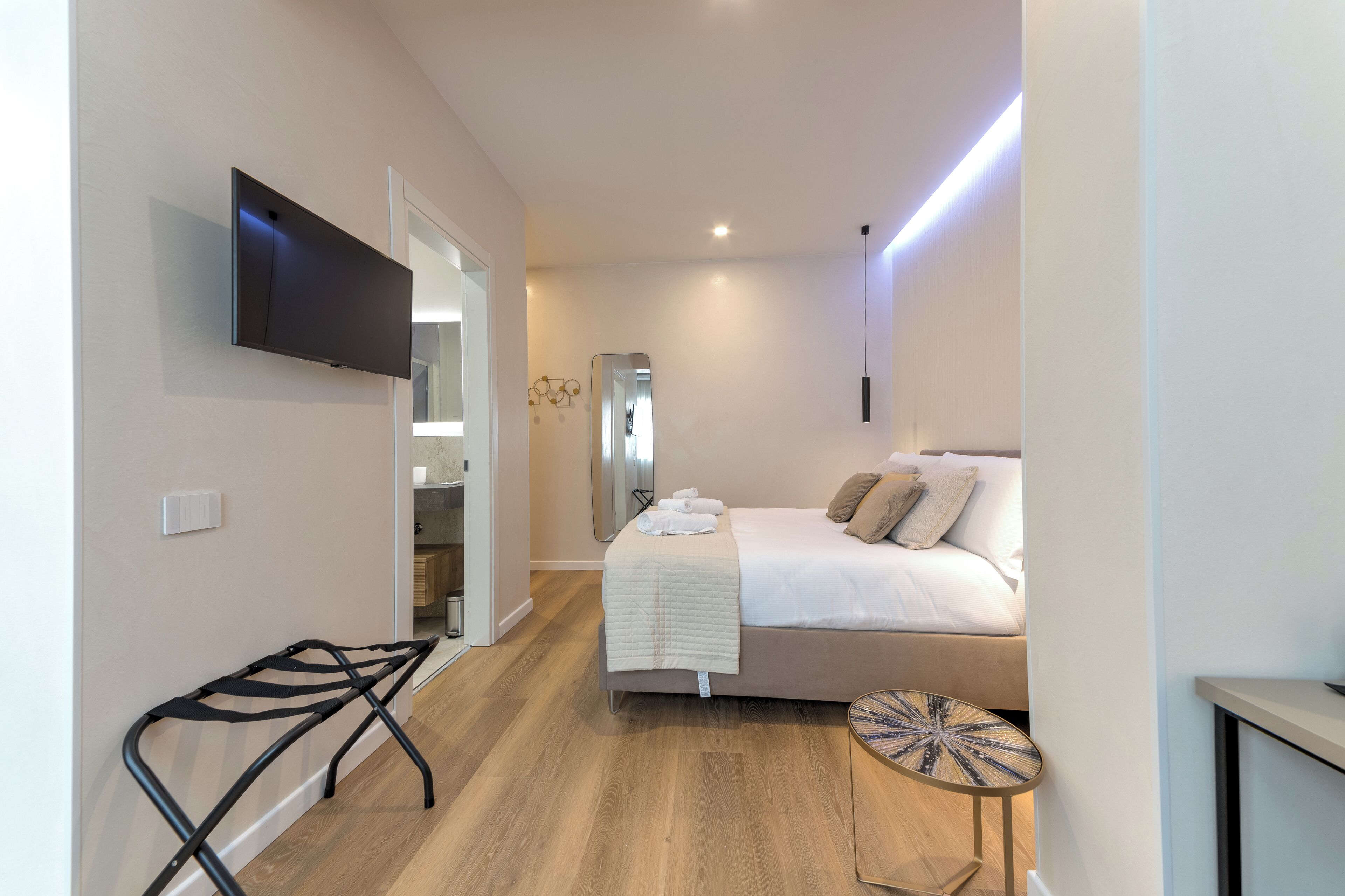 Une chambre à coucher moderne avec un lit, une table de chevet et un téléviseur fixé au mur.