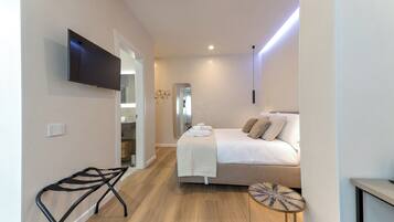 Un dormitorio moderno con cama, mesita de noche y televisor montado en la pared.