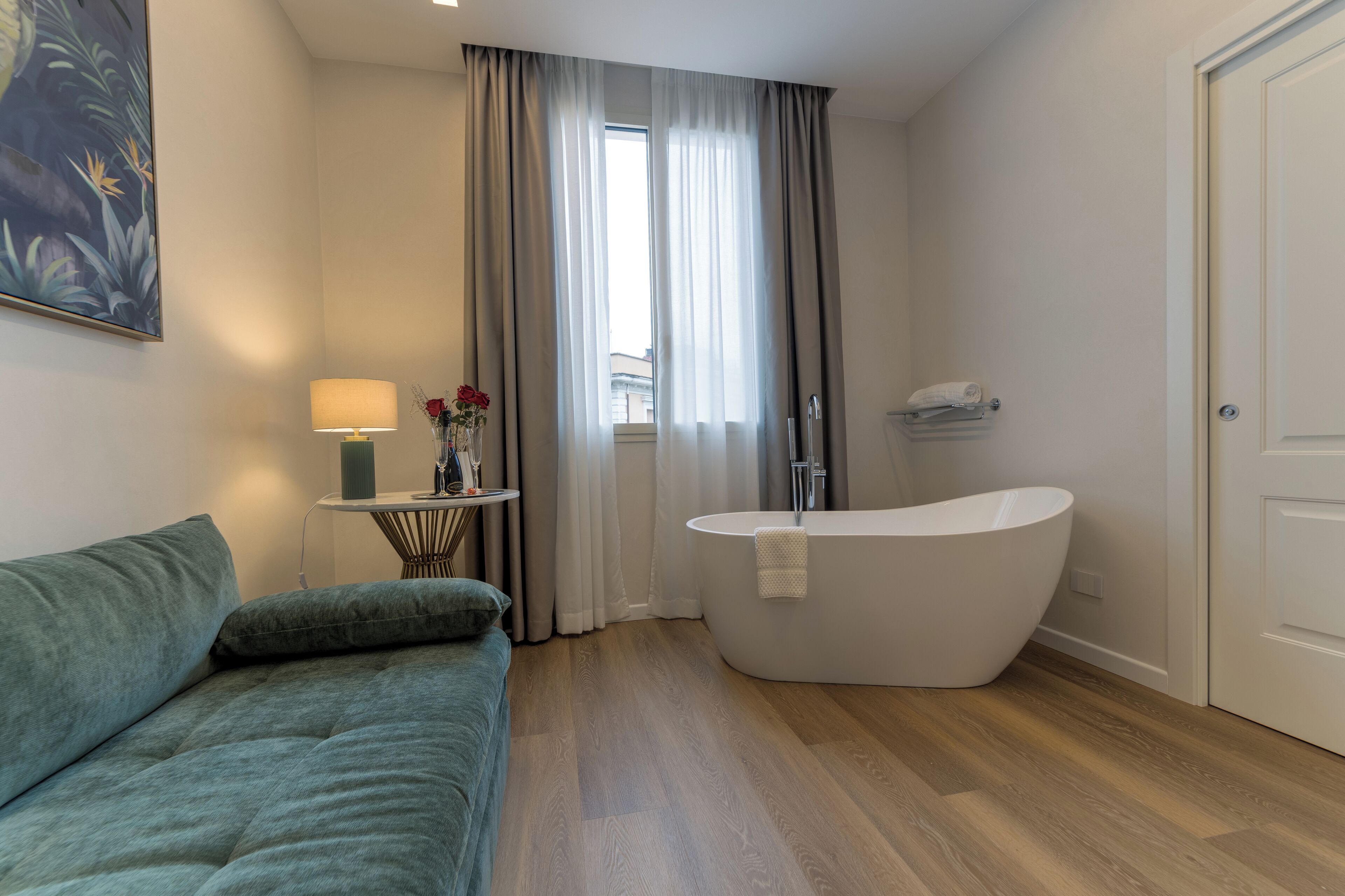 Un baño moderno con una bañera independiente, una mesita con una lámpara y un sofá.