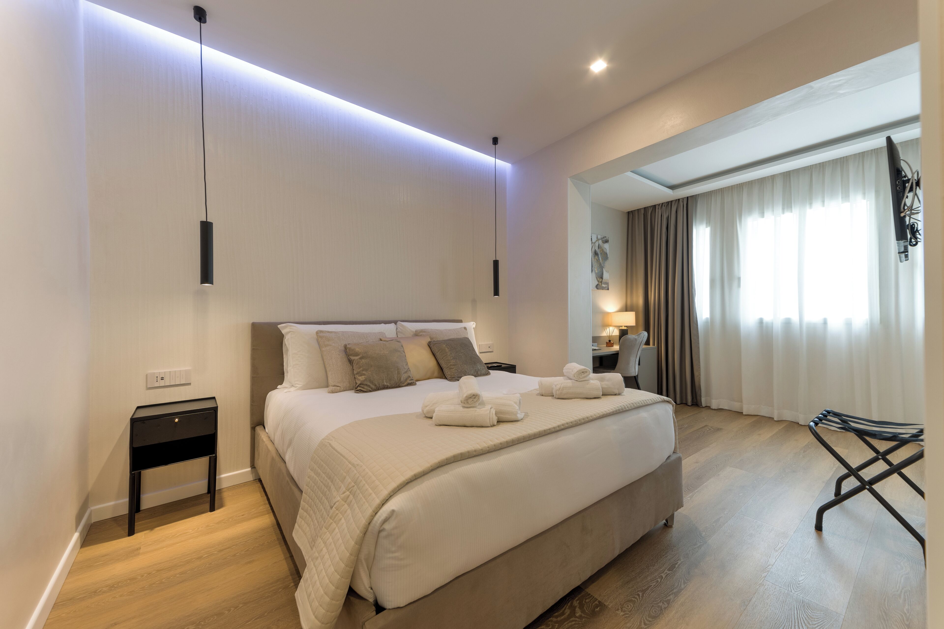 A modern hotel room with a large bed, bedside tables, a desk, and a chair.