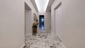 A hallway with a marble floor, white walls, and a ceiling light. - GH Villa Poerio (Rome)
