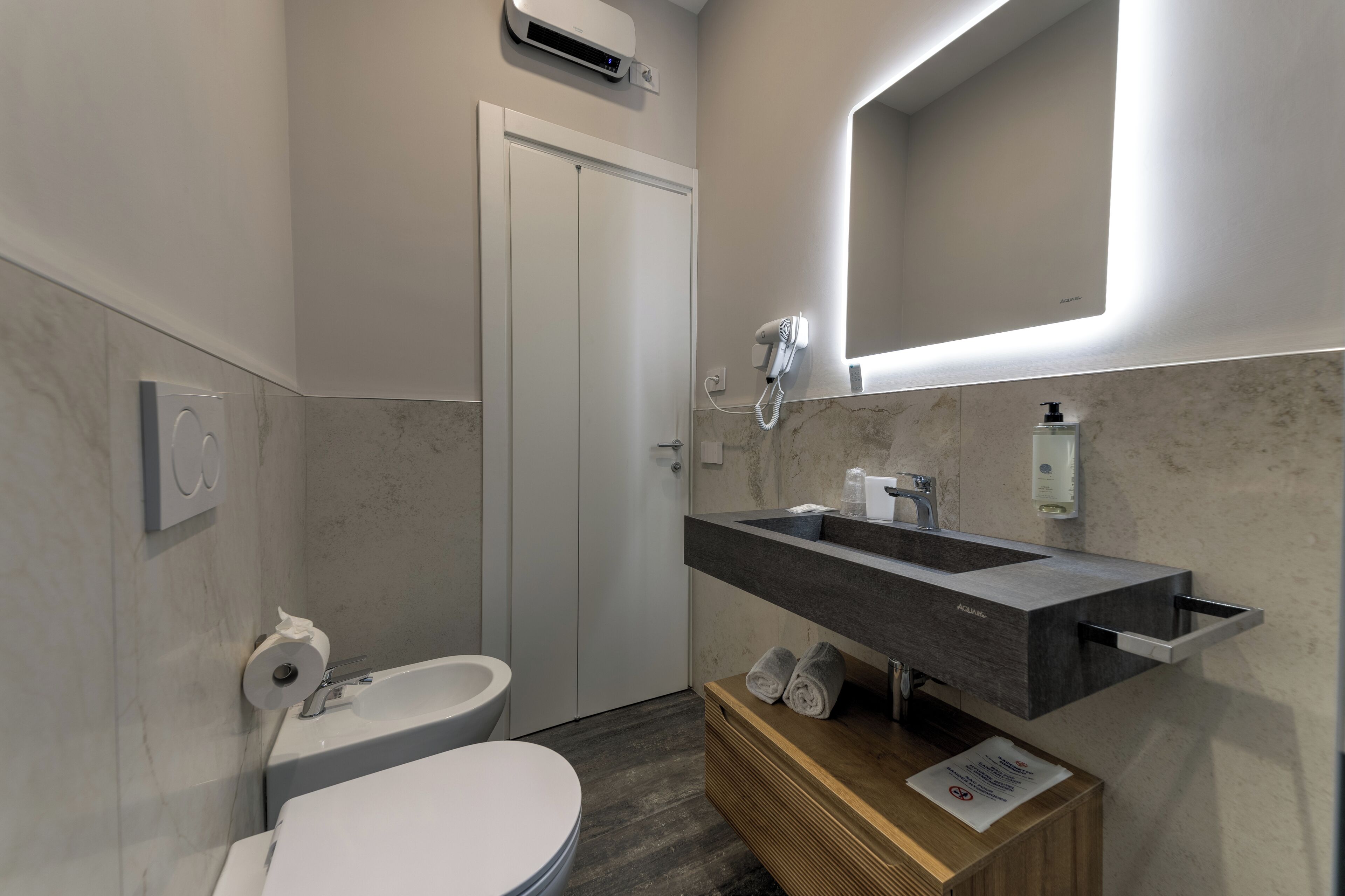 Un bagno moderno con il water, lavandino e specchio.