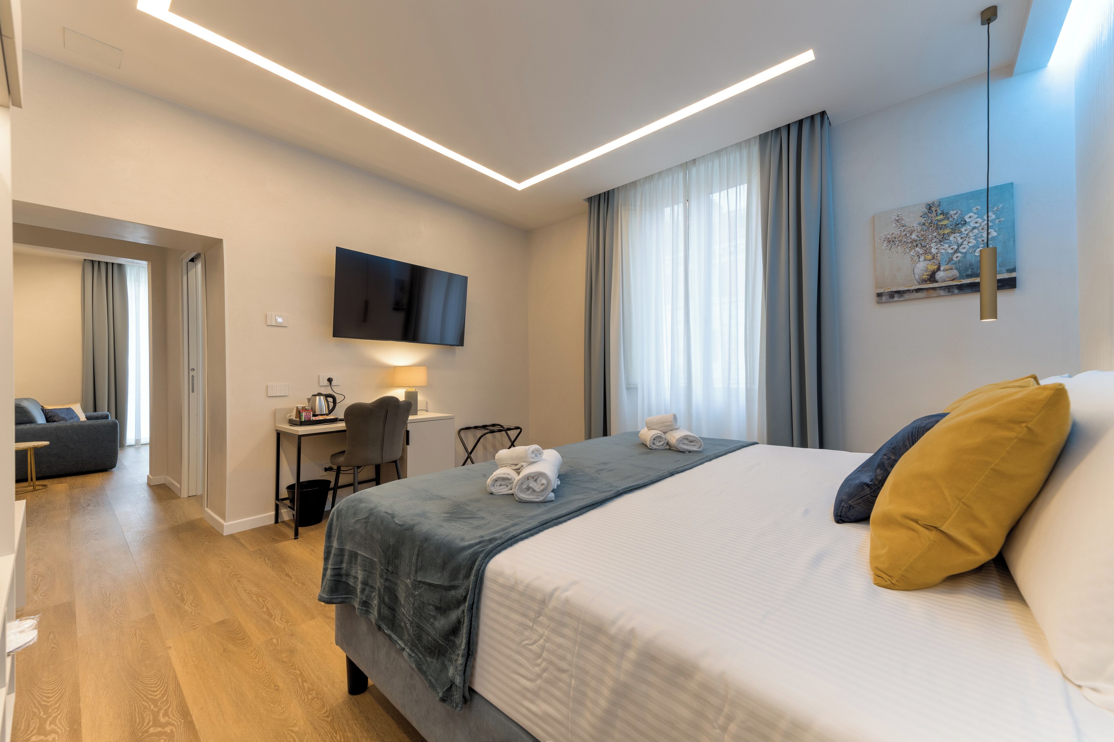 Une chambre d’hôtel moderne équipée d’un lit, d’un bureau, d’une chaise et d’un téléviseur fixé au mur.