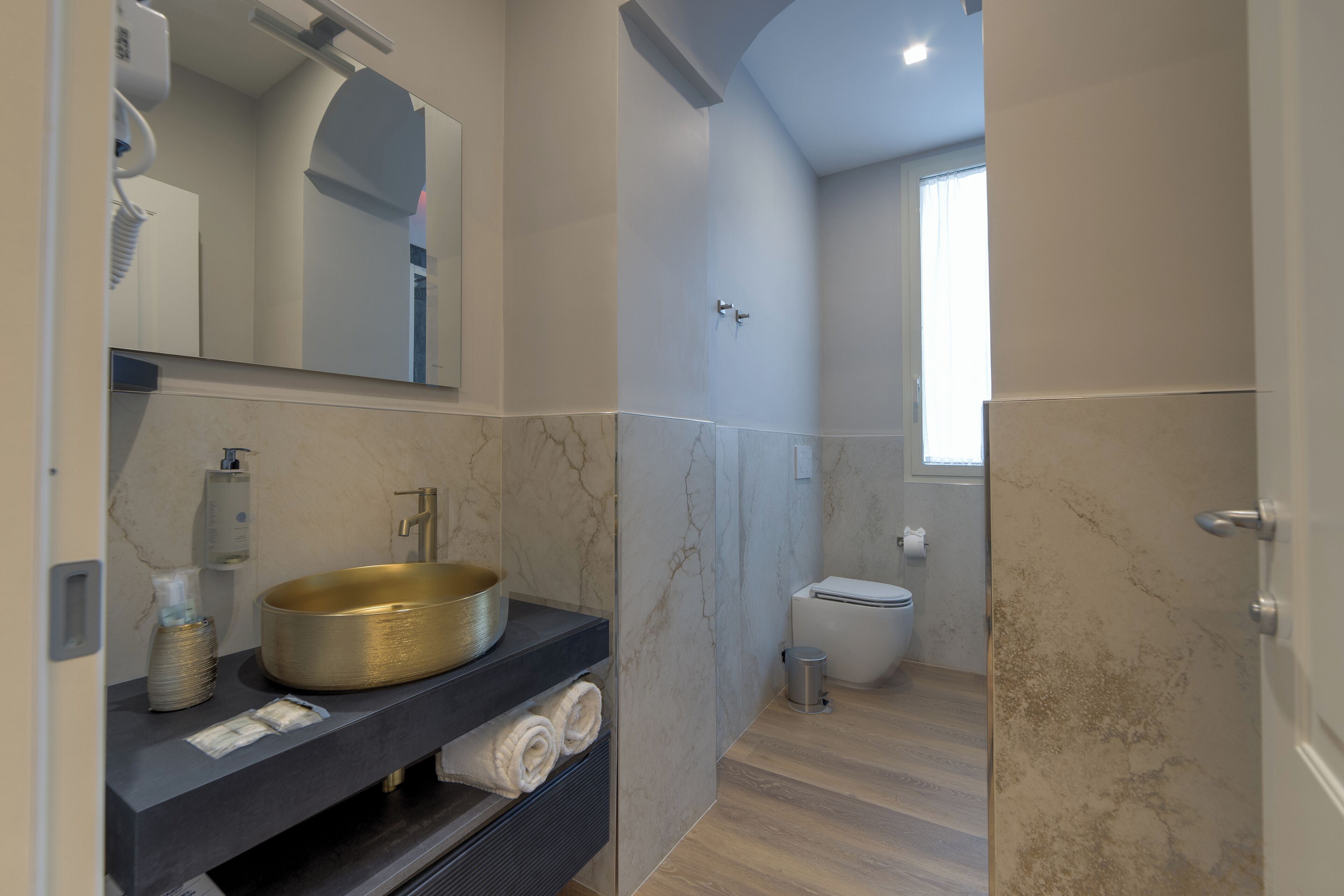 A modern bathroom with a large sink, mirror, and toilet.