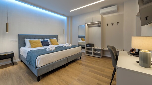 A modern hotel room with a bed, bedside table, and a desk with a lamp. - GH Villa Poerio (Rome)