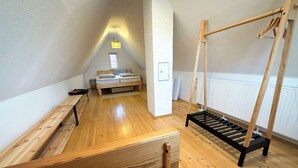 Une pièce avec un lit en mezzanine, un banc en bois, une balançoire et un radiateur.