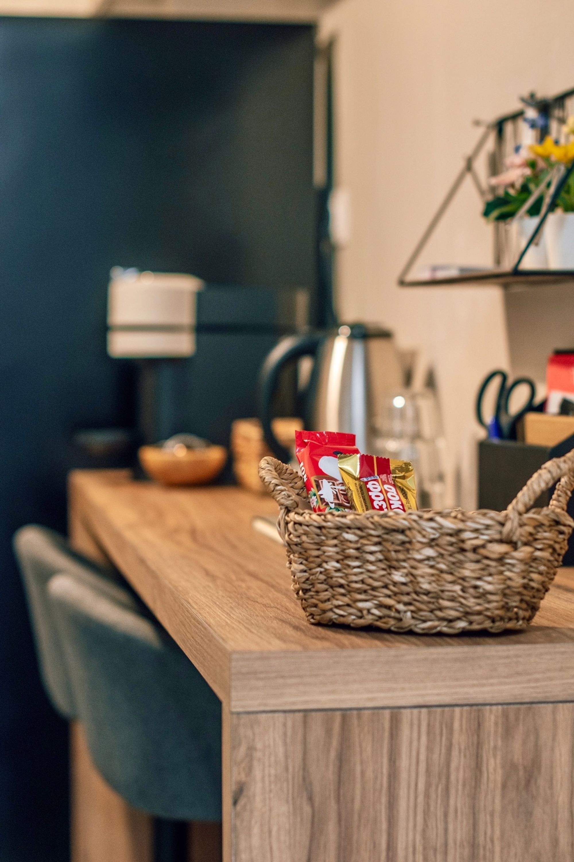Een aanrecht met een gevlochten mand die snacks, een waterkoker en een lamp bevat.