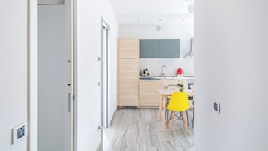 Een moderne keuken met houten kastjes, een eettafel met stoelen en een zichtbare spoelbak.
