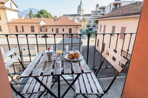 A balcony with a table set for breakfast, including croissants and orange juice. - Casa Gaia e Giulio WelcHome (Verbania)
