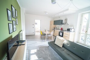 A modern apartment with a dining area, kitchenette, and a living room with a sofa. - Casa Gaia e Giulio WelcHome (Verbania)