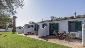 A two-story building with a patio area, outdoor seating, and a small garden. - Jardim do Sul Apt 6 (Olhao)