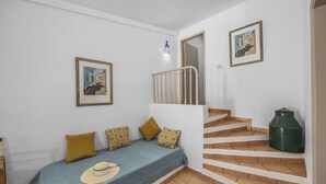 A bedroom with a bed, a staircase, and two framed pictures on the wall. - Jardim do Sul Apt 6 (Olhao)