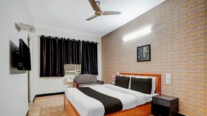 A hotel room with a bed, a nightstand, a ceiling fan, a TV, and a window with curtains. - Hotel O Clock Tower Ludhiana (Ludhiana)
