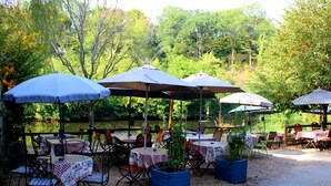 Mesas al aire libre con sombrillas, sillas y plantas en macetas.