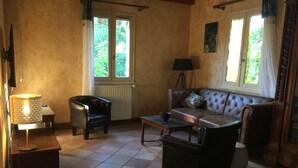 Sala de estar con sofá, sillón, lámpara y radiador.