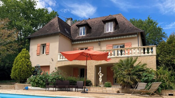 Una casa de dos pisos con piscina, muebles de exterior y una estatua.