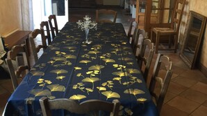 Un comedor con una mesa larga, sillas, una araña y una estantería.