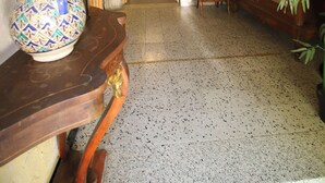 A hallway with a stone wall, a wooden chair, a wooden table with a decorative vase, and a mirror. - Auberge de la Couronne (Lablachère)