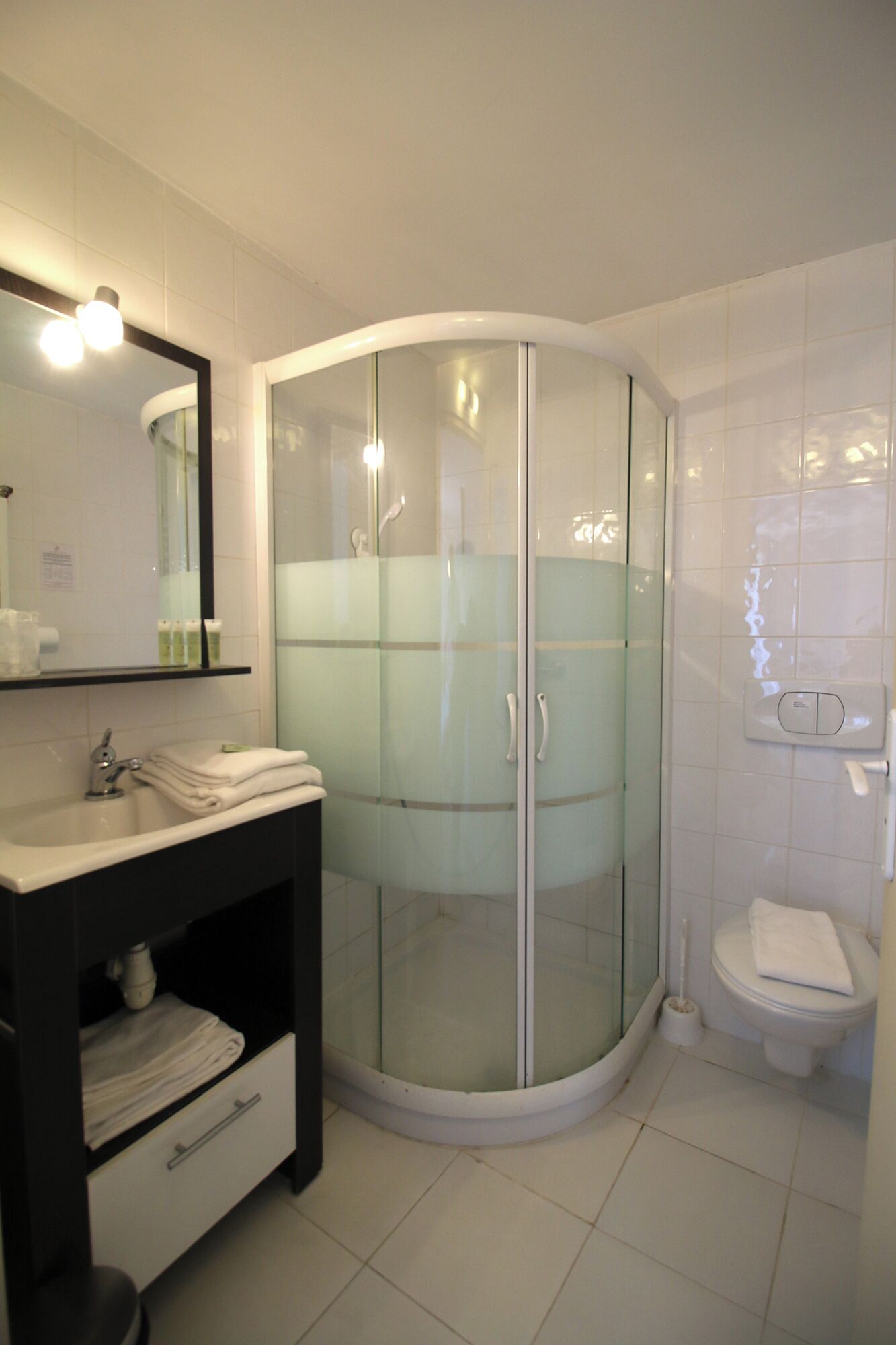 Et badeværelse med bruseniche, vask med spejl og toilet.